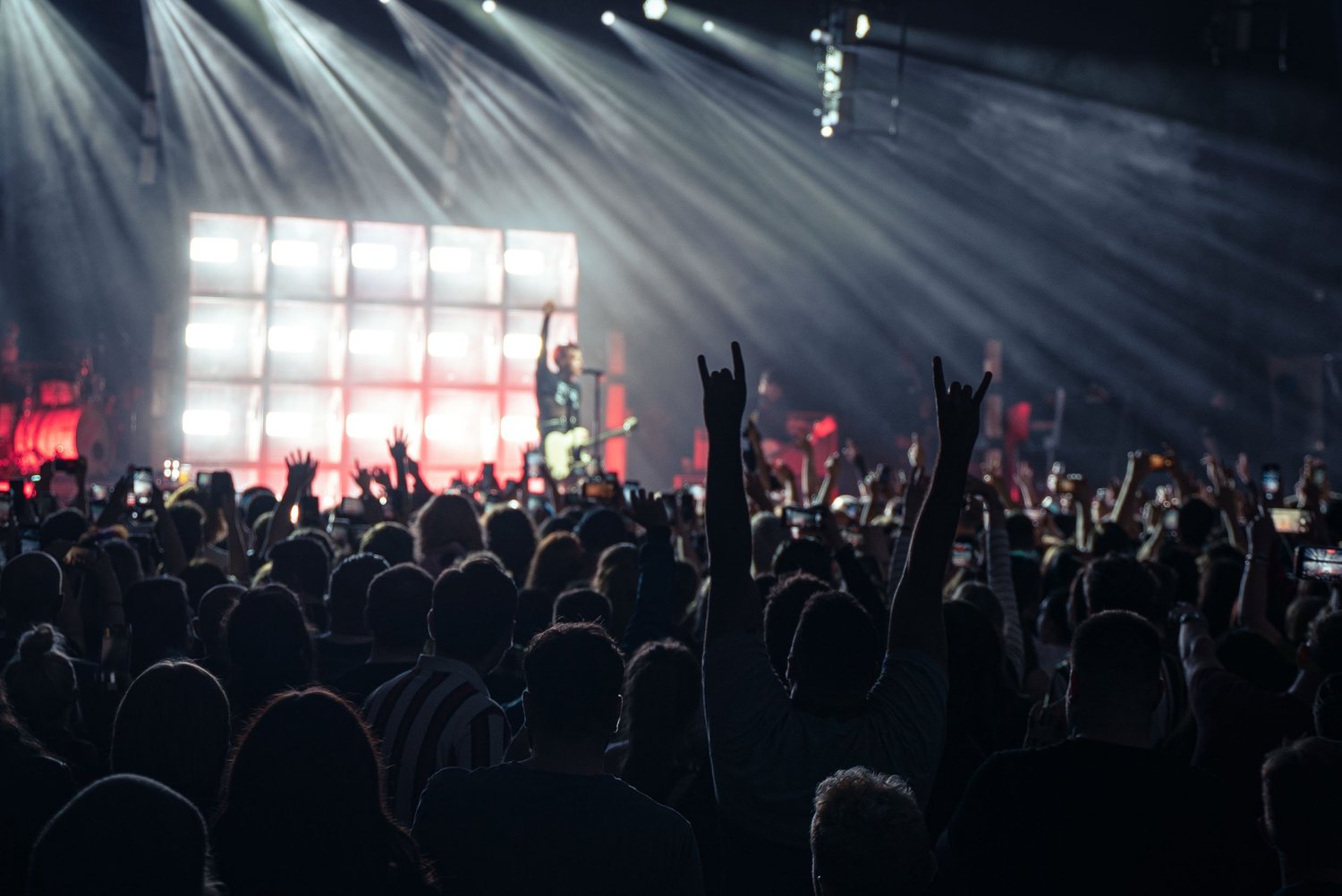 Crowd at a rock concert with raised hands and stage lighting