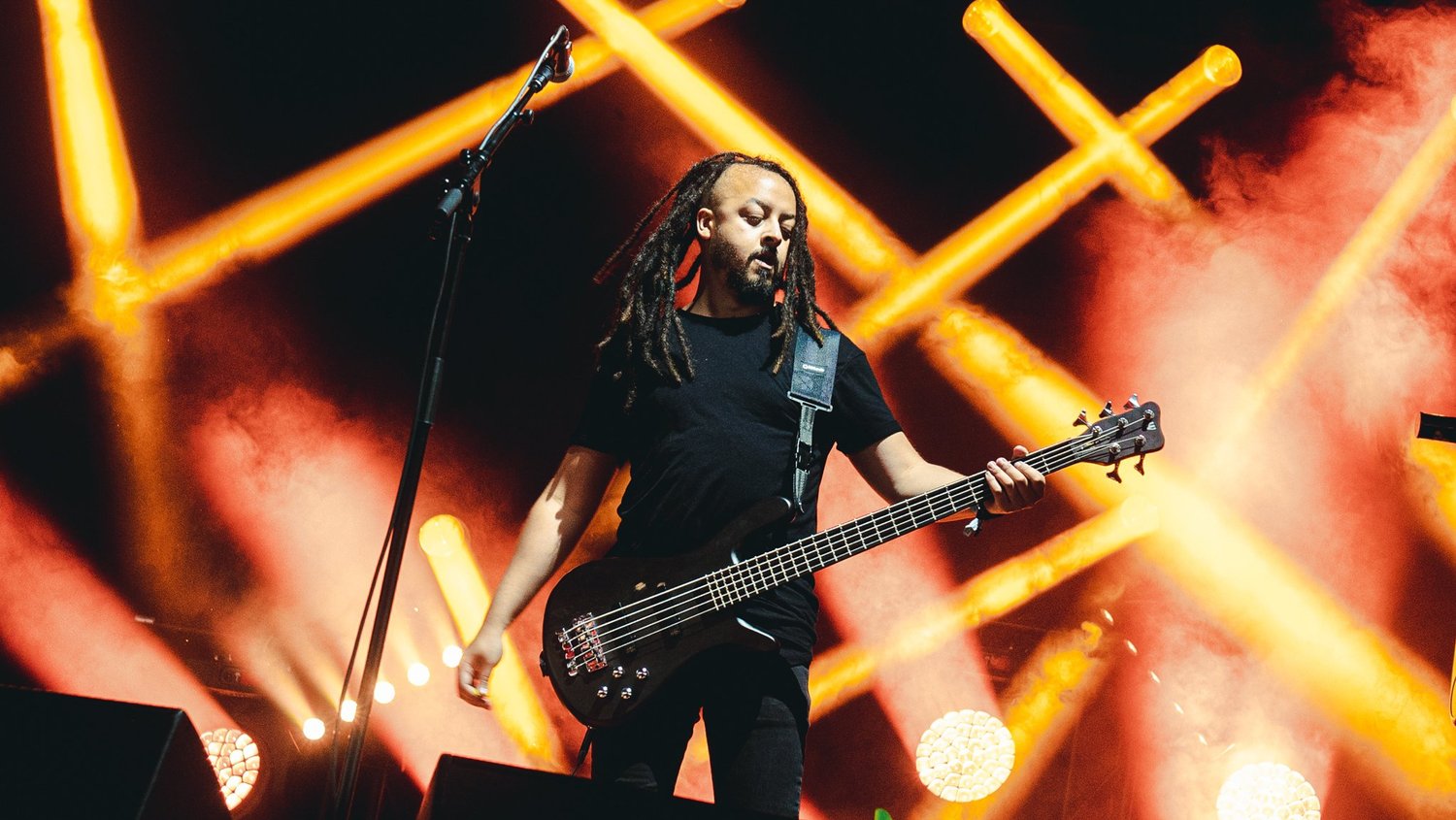 Musician playing guitar on stage with orange lights